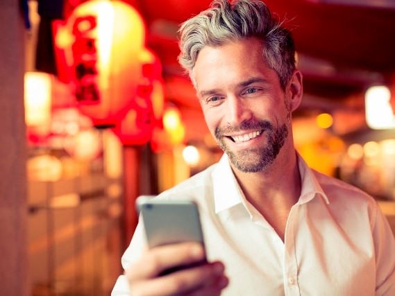 Mann schaut auf sein Smartphone in der Hand